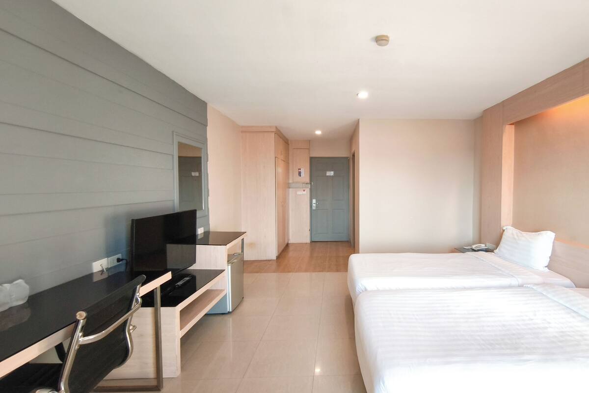 Una habitación de hotel moderna con una cama, un escritorio con una silla, un televisor y una puerta que da a un baño.