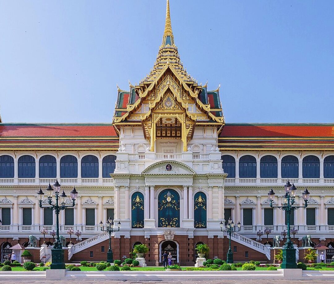 A grand building with a prominent golden spire, large arched windows, and a central entrance with a decorative archway.