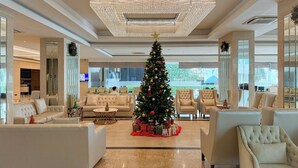 A spacious lobby with a large Christmas tree, comfortable seating, and a modern chandelier. - Avana Residence (Bangkok)