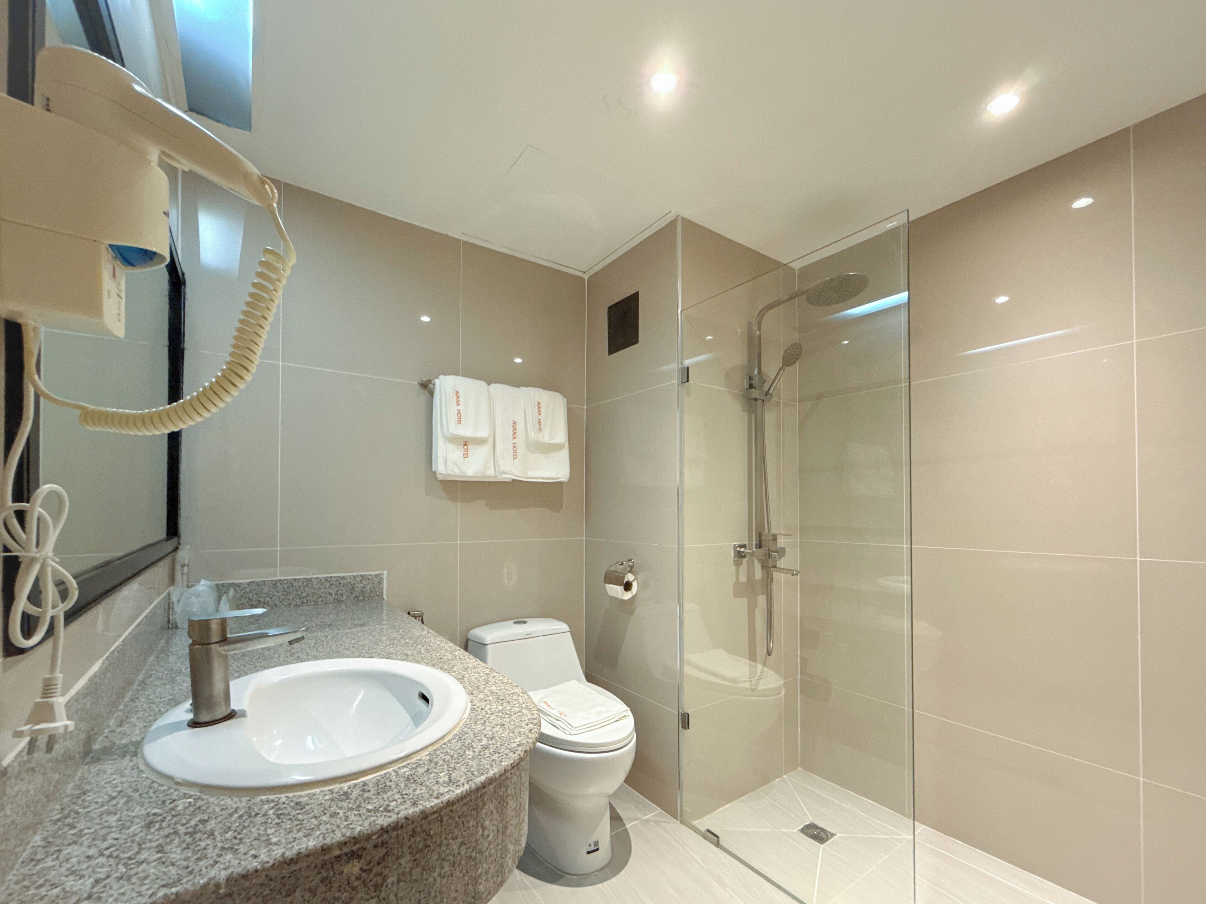 Un baño moderno con lavamanos de granito, inodoro y cabina de ducha con mampara de vidrio.