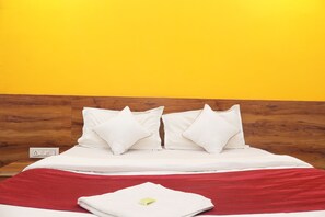 A hotel room with a wooden headboard, white bedding, and a red throw blanket. - HOTEL APOLLO (Ahmedabad)
