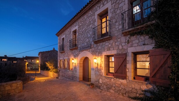 Un edificio de piedra con puertas y ventanas de madera arqueadas, iluminado por una cálida luz.