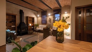 Un salón acogedor con chimenea, muebles de madera y un jarrón con flores amarillas sobre una mesa de madera.