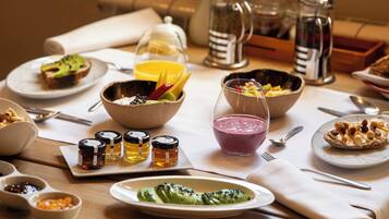 A breakfast setting with various dishes, including toast with avocado, a bowl of fruit, and a glass of smoothie.