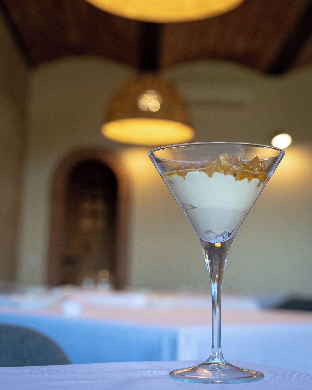 A martini glass with a dessert on a table in a restaurant.