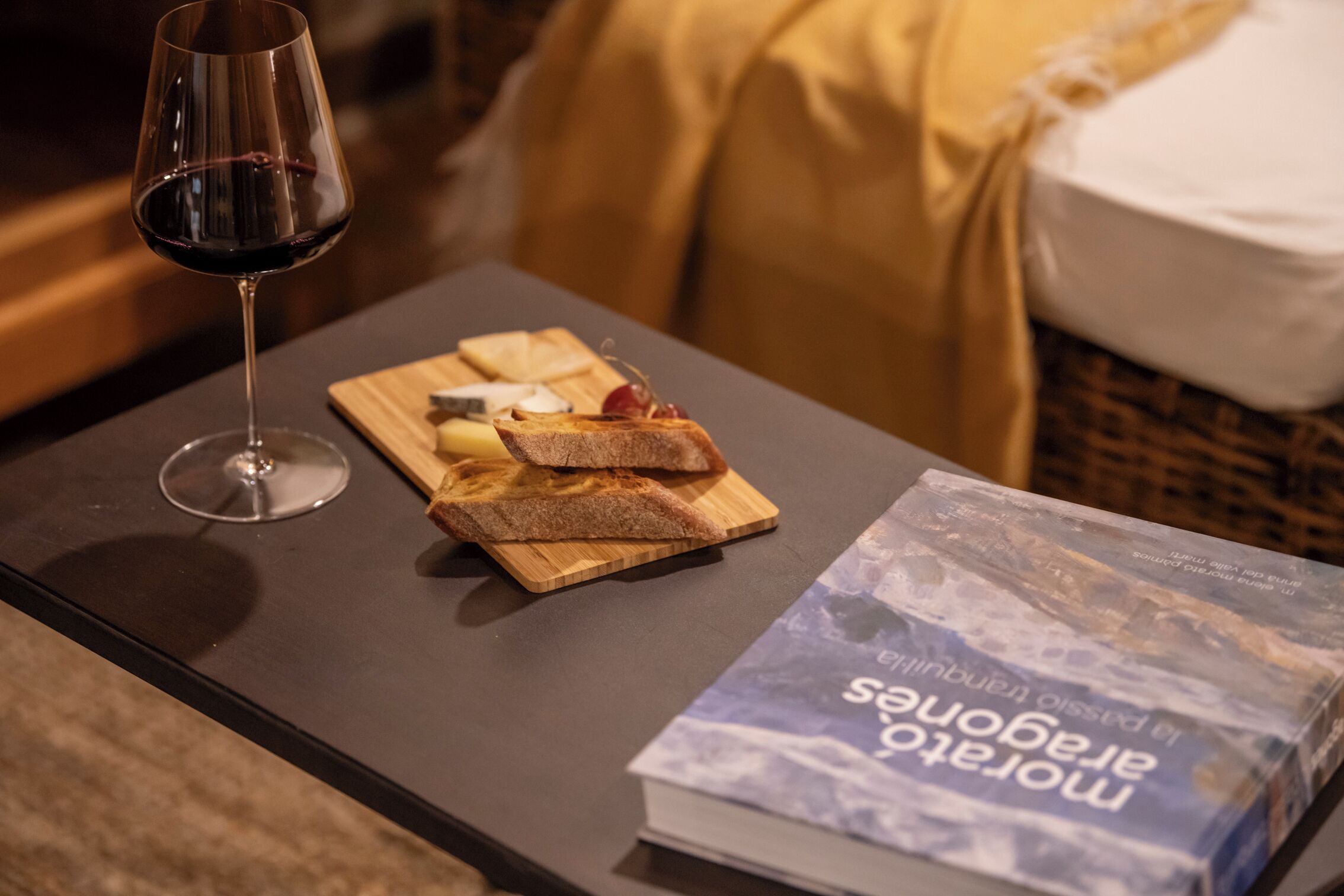 A table with a wine glass, a wooden board with bread and cheese, and a book titled "El Salvador".