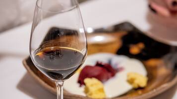 A close-up of a wine glass on a table with a plate of food in the background.