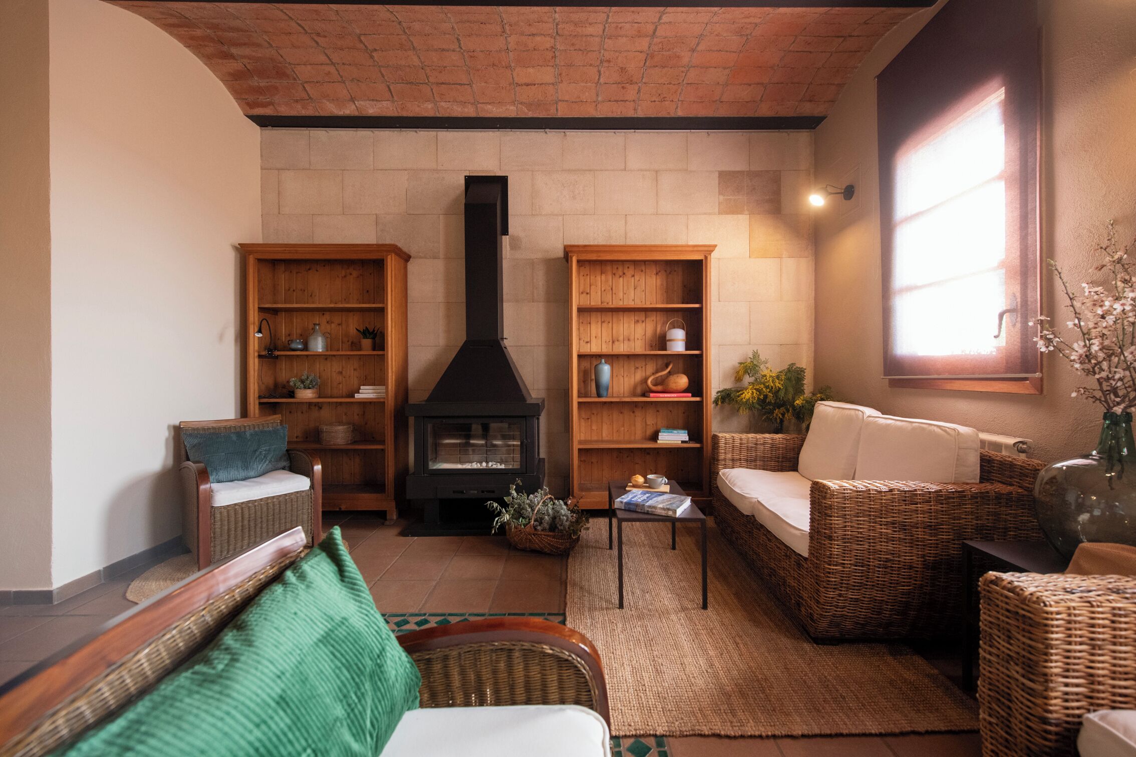 A cozy living room with a fireplace, wicker furniture, and built-in wooden shelves.