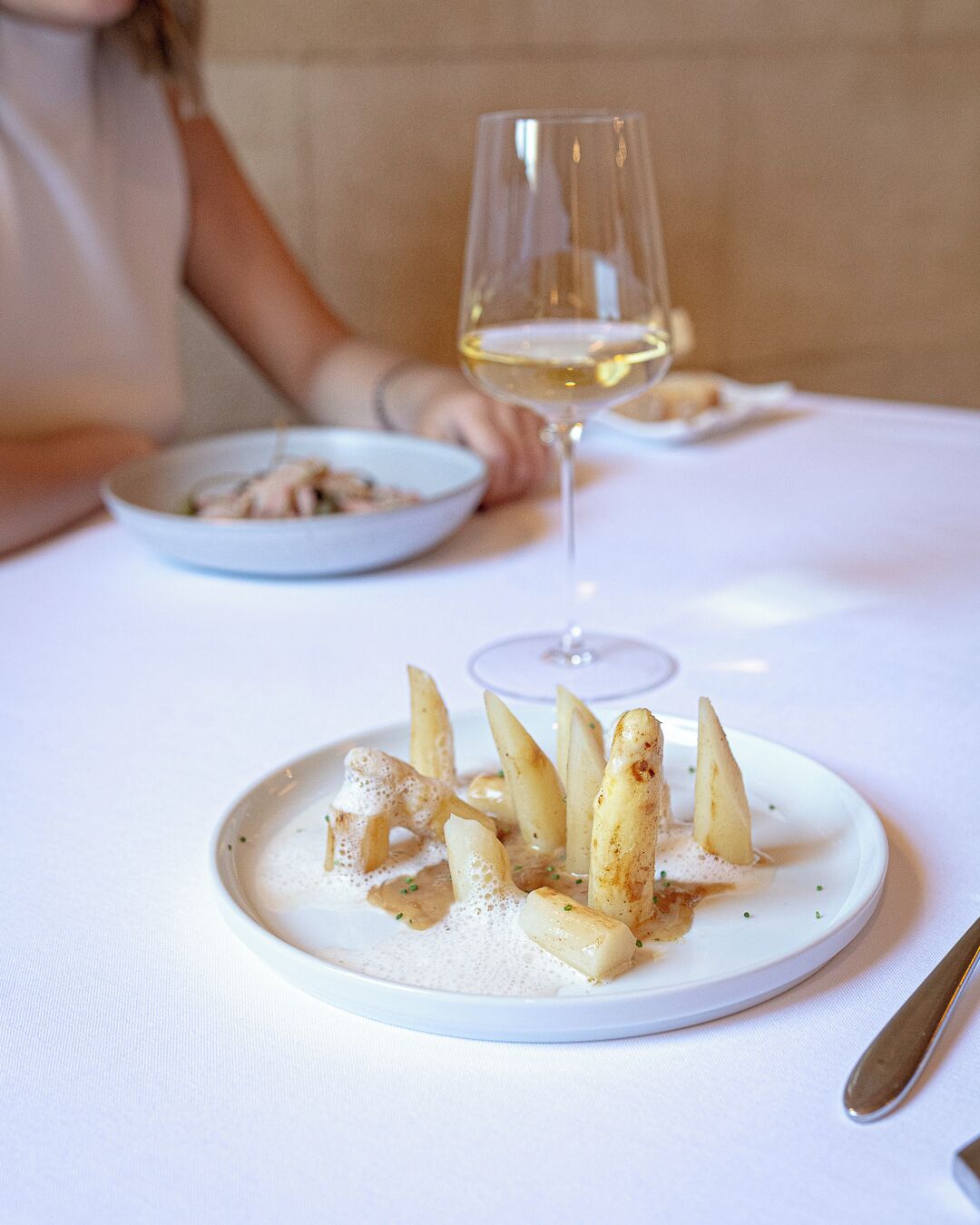 A plate of food with a glass of white wine on a table.