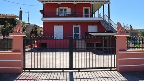 Ein zweistöckiges Gebäude mit roter Fassade, einem Balkon und einem befestigten Eingangsbereich.