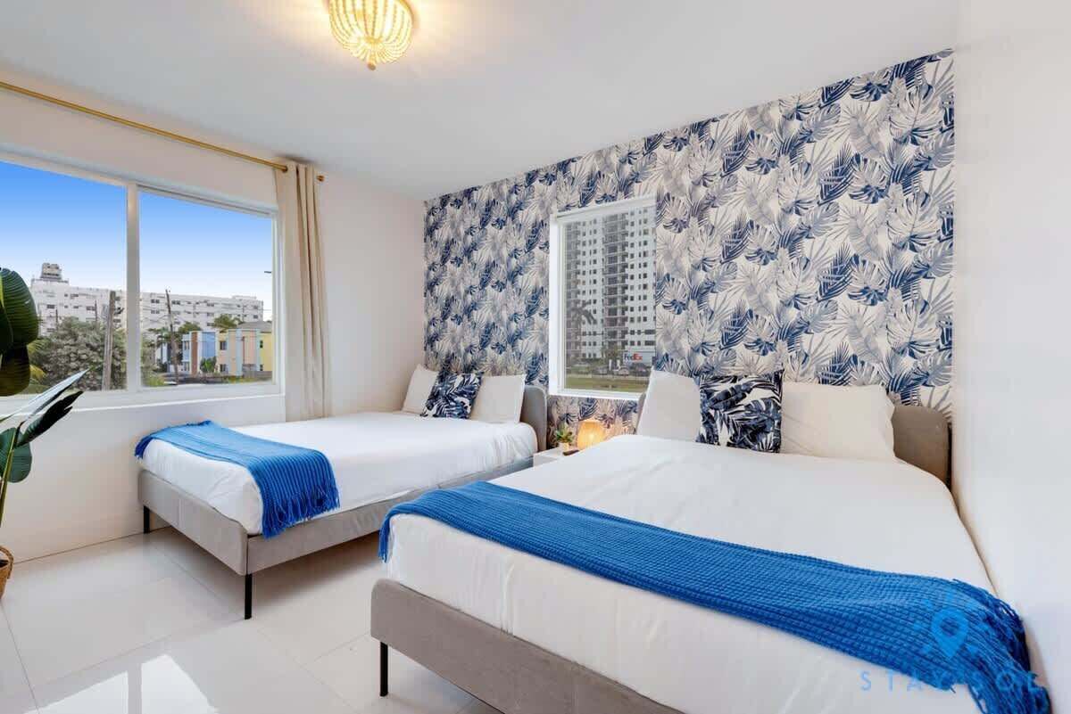 Ein Hotelzimmer mit zwei Betten, einem großen Fenster und Blick auf die Stadt.