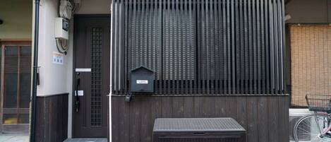 A building entrance with a dark wooden gate, a mailbox, and a bicycle parked nearby.