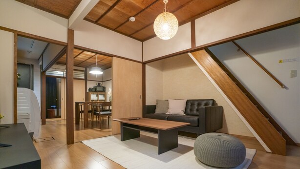 Ein modernes Wohnzimmer mit Holzboden, einer Couch, einem Couchtisch und einer Pendelleuchte.