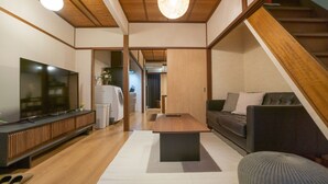 Ein modernes Wohnzimmer mit Fernseher, Sofa, Couchtisch und Treppe.