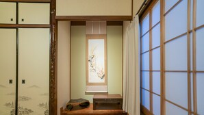 Ein traditioneller japanischer Raum mit Schiebetüren, einem Tatami-Boden, einem kleinen Holztisch und einem Fenster mit Bergblick.