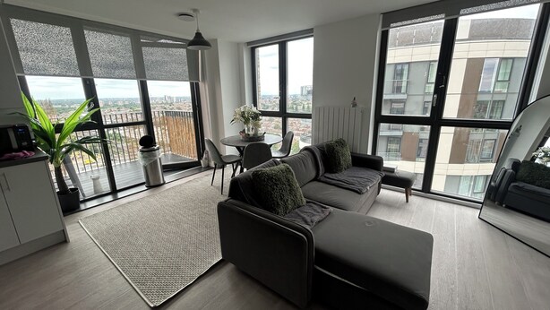 Uma sala de estar moderna com um sofá, uma mesa de jantar e uma grande janela com vista para a cidade.