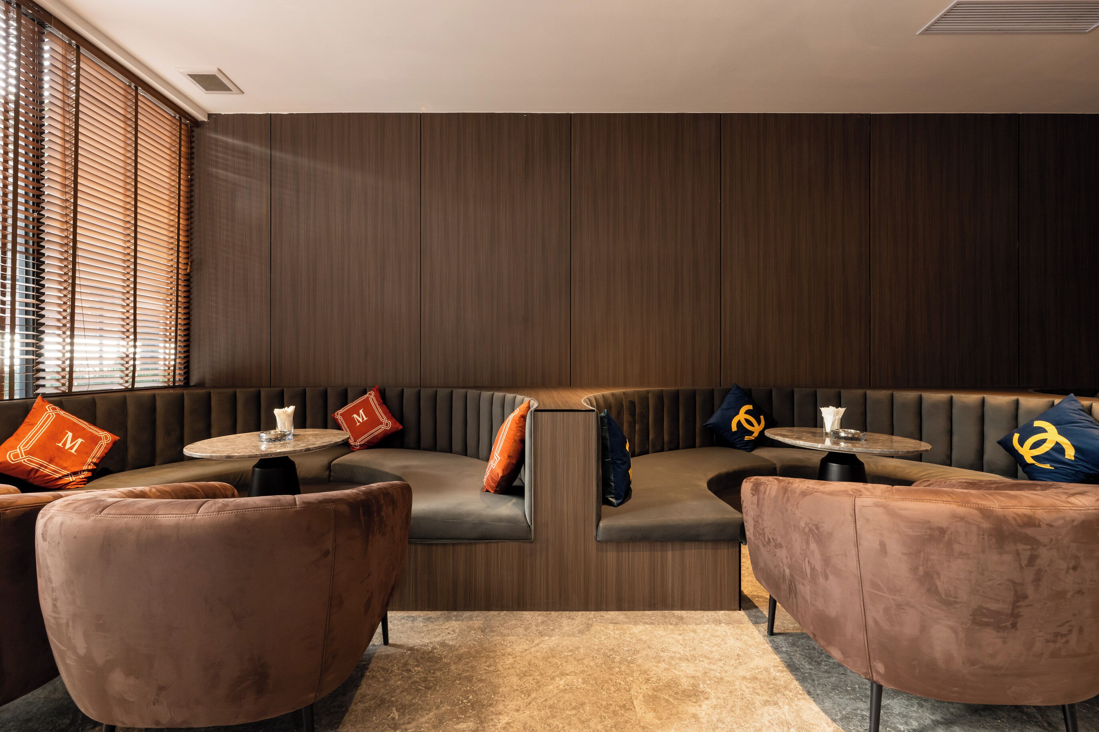Un área de estar moderna con un sofá curvo, dos mesas redondas y sillones a juego.
