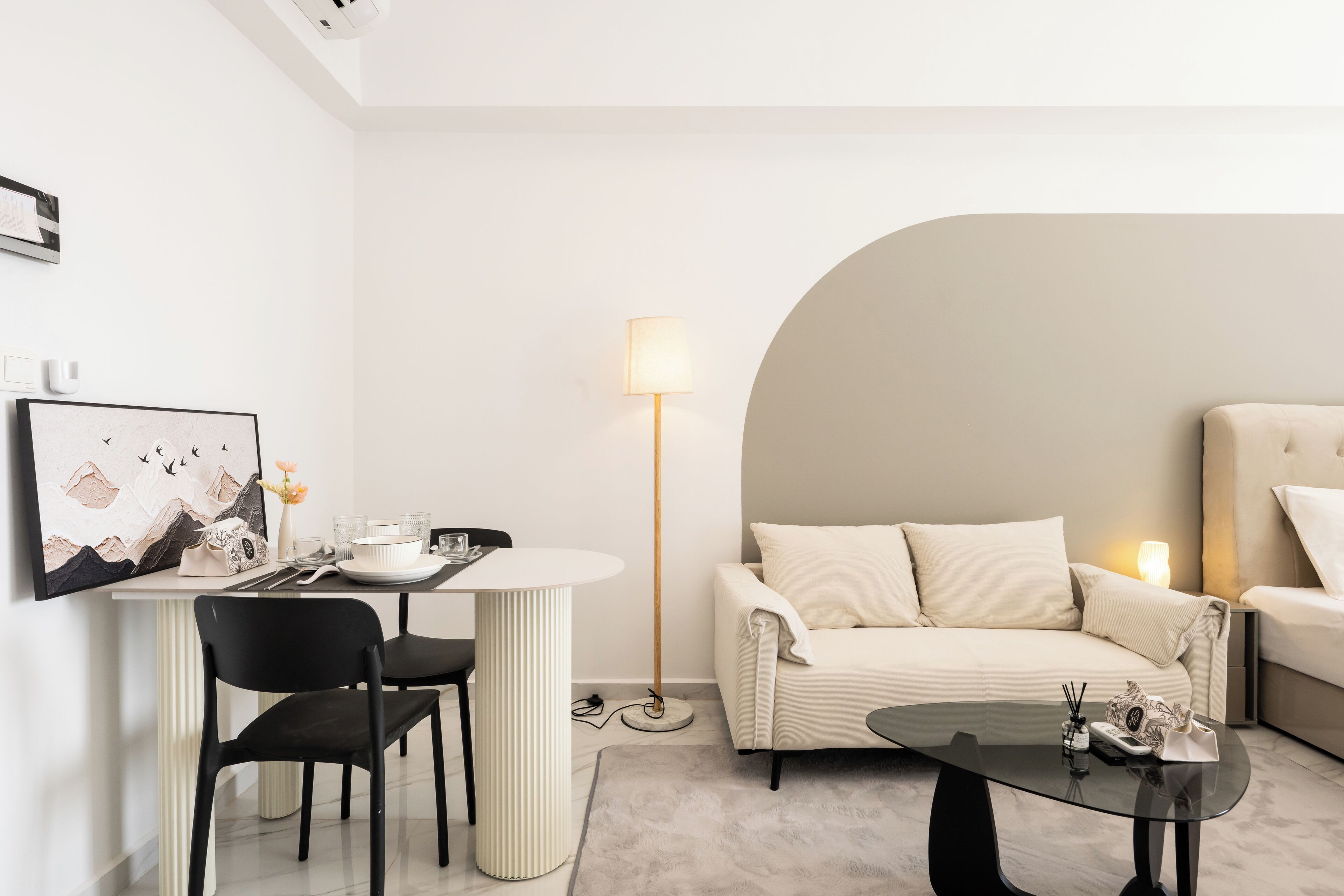 A modern, minimalist room with a dining table, two chairs, a sofa, and a coffee table.