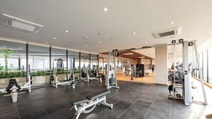 Ein modernes Fitnessstudio mit unterschiedlichen Trainingsgeräten, großen Fenstern und einem aufgeräumten, großzügigen Raumkonzept.