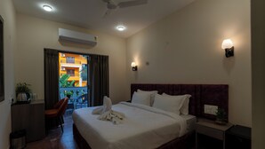 A hotel room with a bed, a desk, a chair, a ceiling fan, and a wall-mounted lamp. - Evoke Express Candolim (Candolim)