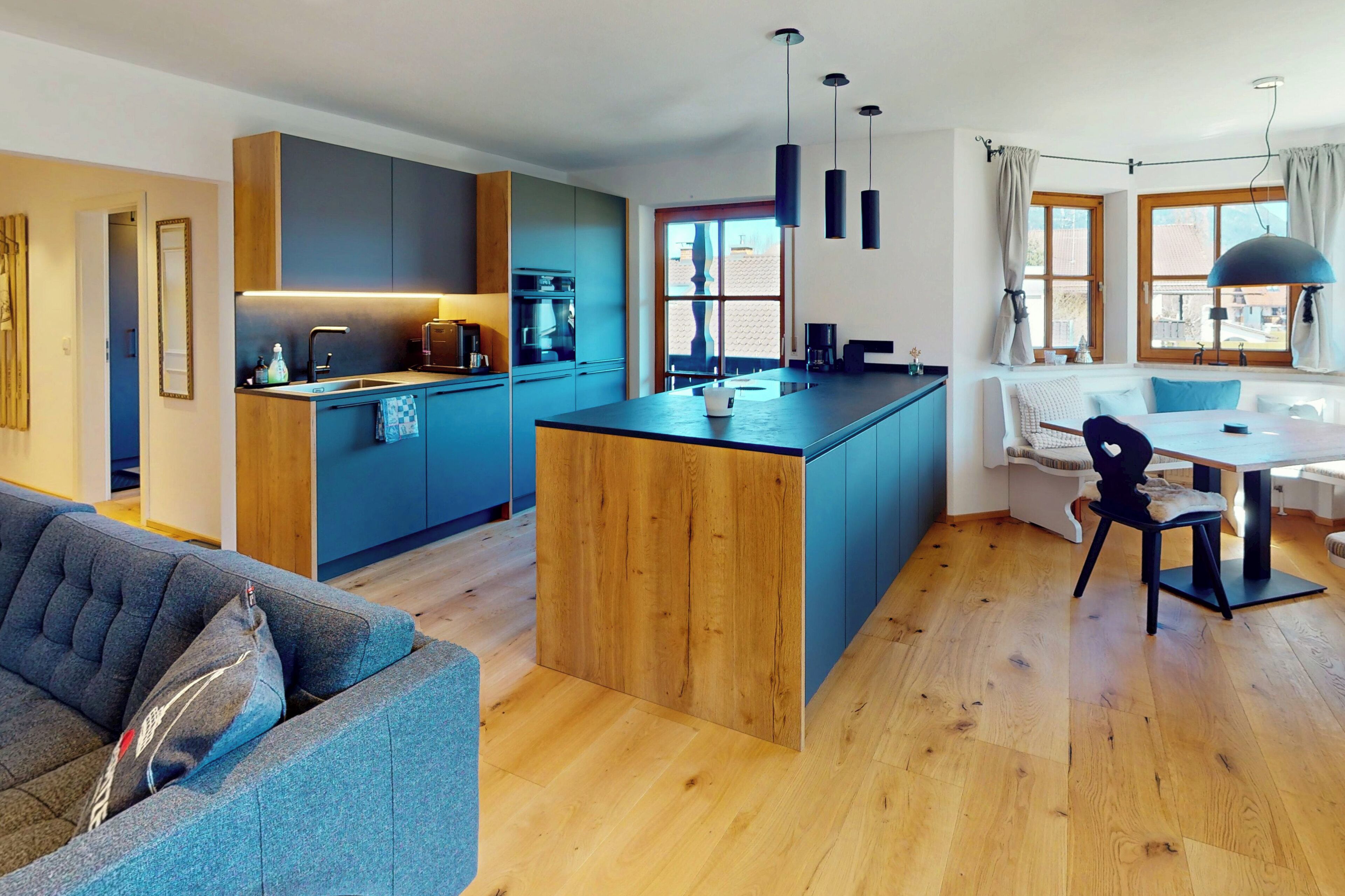 Eine moderne Küche mit einer zentralen Kochinsel, Holzboden und einem Essbereich mit Tisch und Stühlen.