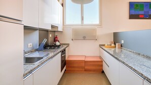 A kitchen with white cabinets, a granite countertop, a stove, a sink, a window with blinds, and a ceiling light. - Ca' dell'Arte - San Giacomo (Venezia)