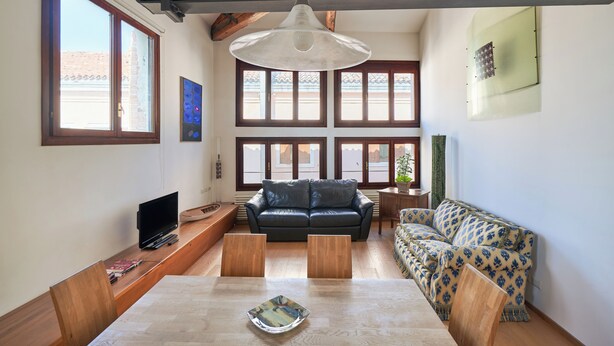 A living room with a sofa, a dining table, and a TV. - Ca' dell'Arte - San Giacomo (Venezia)