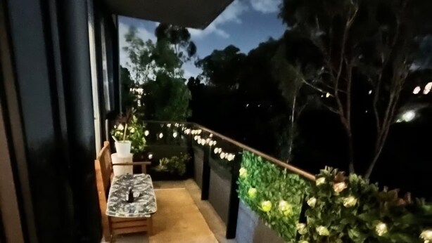 Eine Terrassenausstattung im Freien mit Tisch und Stühlen, umgeben von Topfpflanzen und einer grünen Rasenfläche aus Kunstgrün.