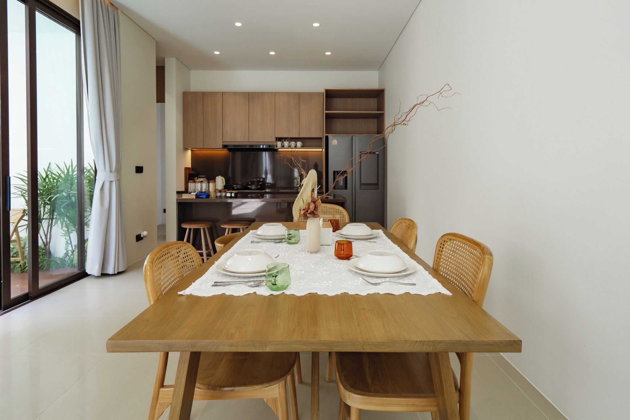 Comedor con mesa de madera preparada para seis personas, rodeado de sillas de mimbre.