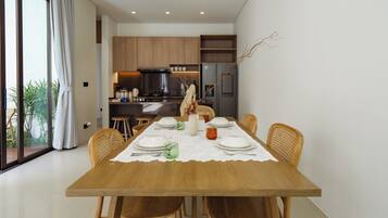 Comedor con mesa de madera preparada para seis personas, rodeado de sillas de mimbre.