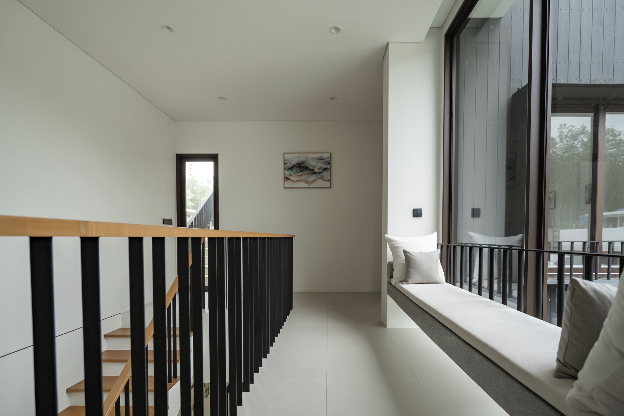 Un interior moderno con una escalera de madera, una pared blanca y un amplio ventanal con vistas.