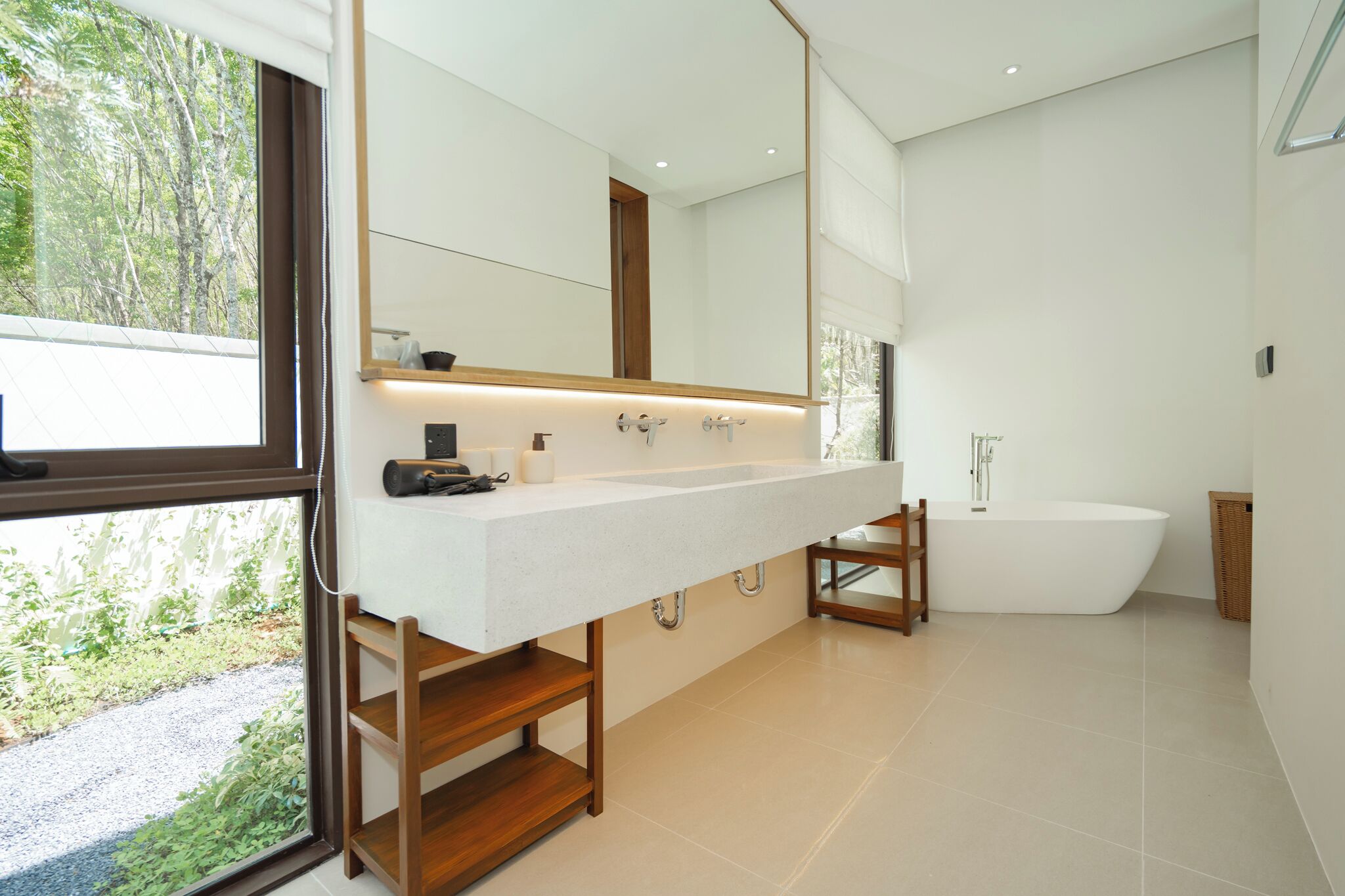 A modern bathroom with a large mirror, a freestanding bathtub, and a wooden vanity.