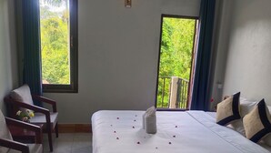 A hotel room with two beds, a sitting area with chairs, a balcony with a railing, and a window with curtains. - Dok Champa Hotel (Vang Vieng)
