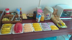 A buffet table with various food items, condiments, and a coffee maker. - Dok Champa Hotel (Vang Vieng)