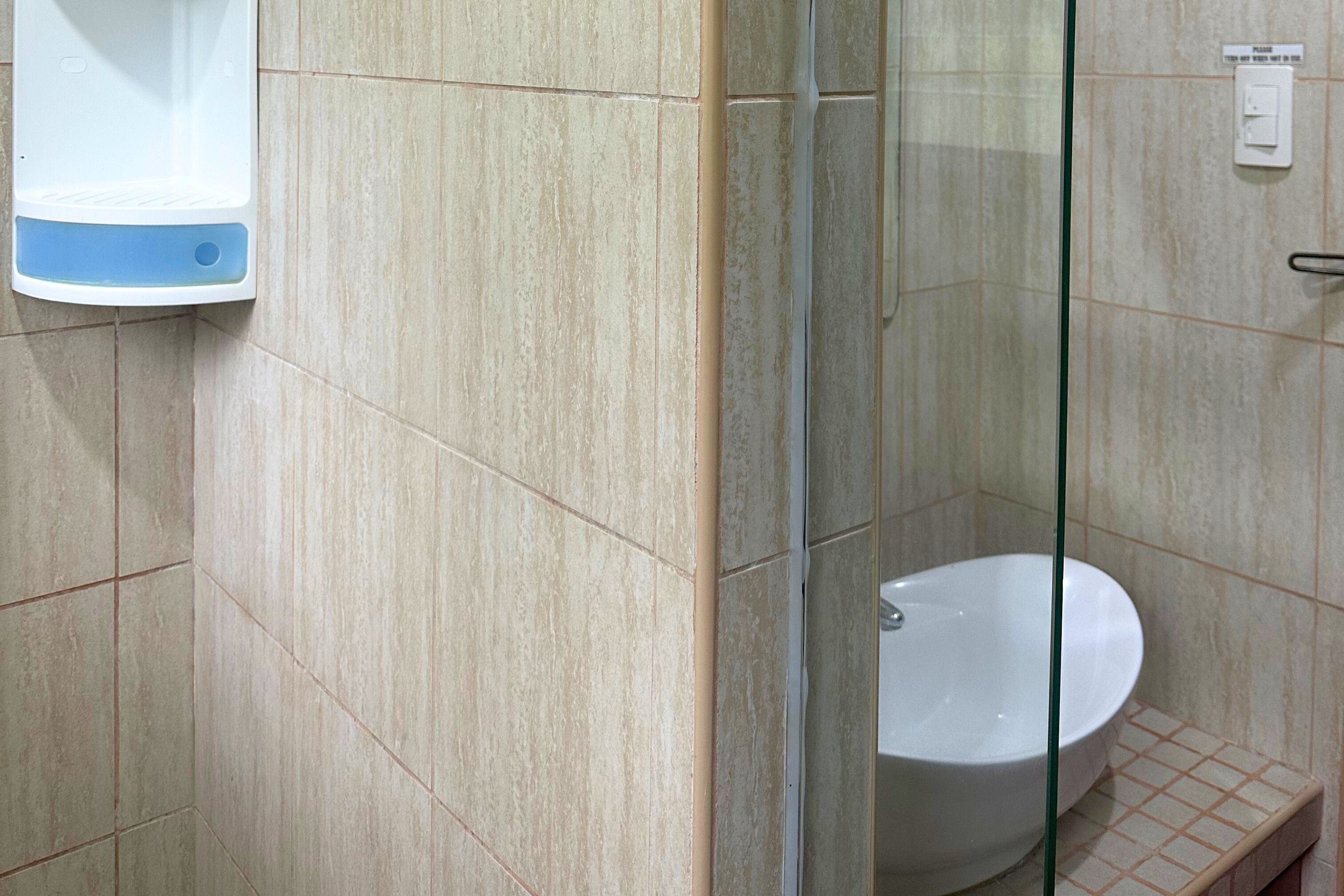A bathroom with a glass shower enclosure, a white sink, and a hand dryer.
