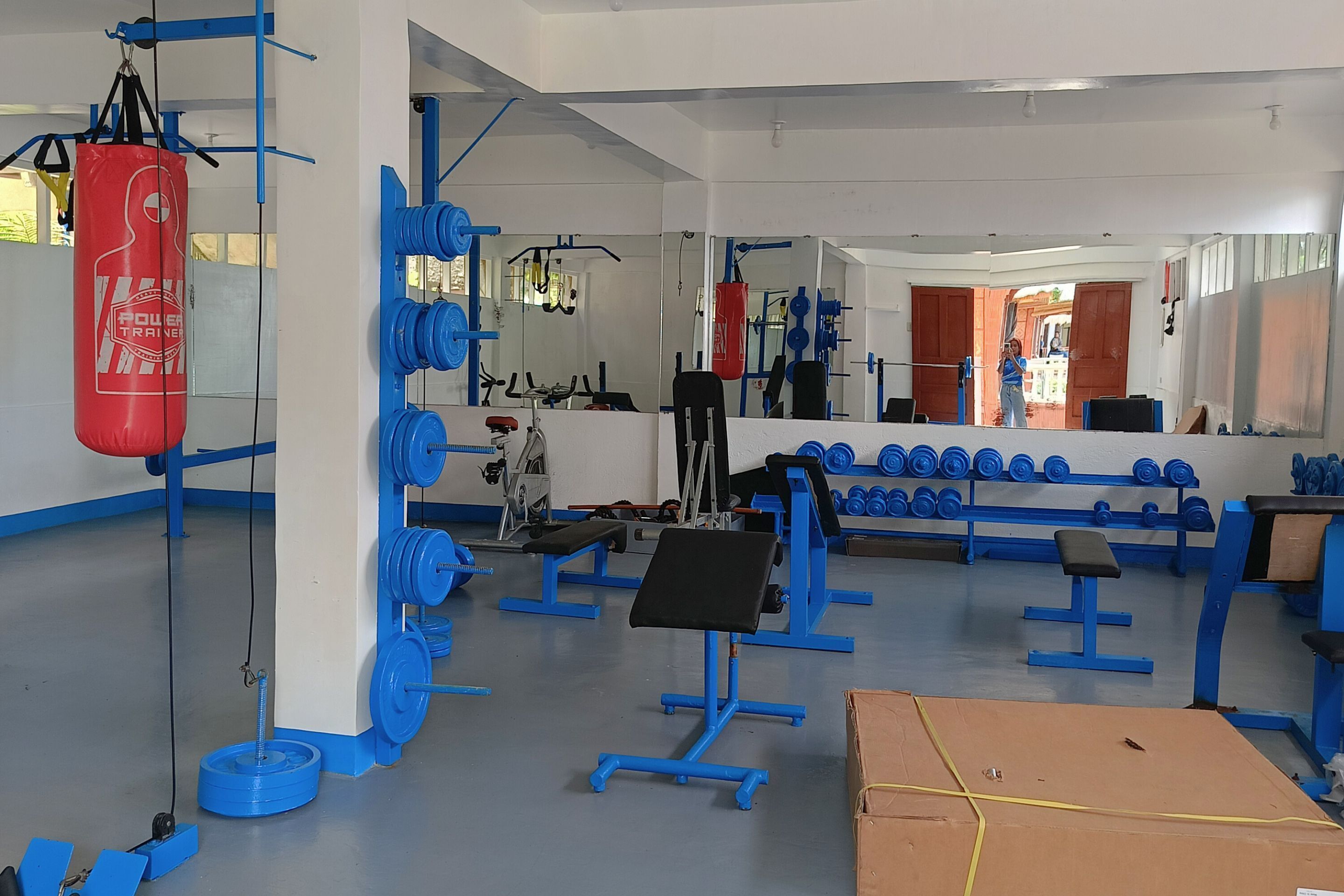 A gym with blue equipment, a red punching bag, and weightlifting stations.