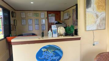 A reception desk at Blue Deep Resort with a sign, certificates, a calendar, and a globe.