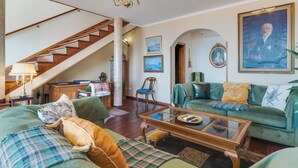 A spacious living room with a staircase, a green sofa set, a wooden coffee table, and a chandelier. - Villa Bom Sucesso (Funchal)