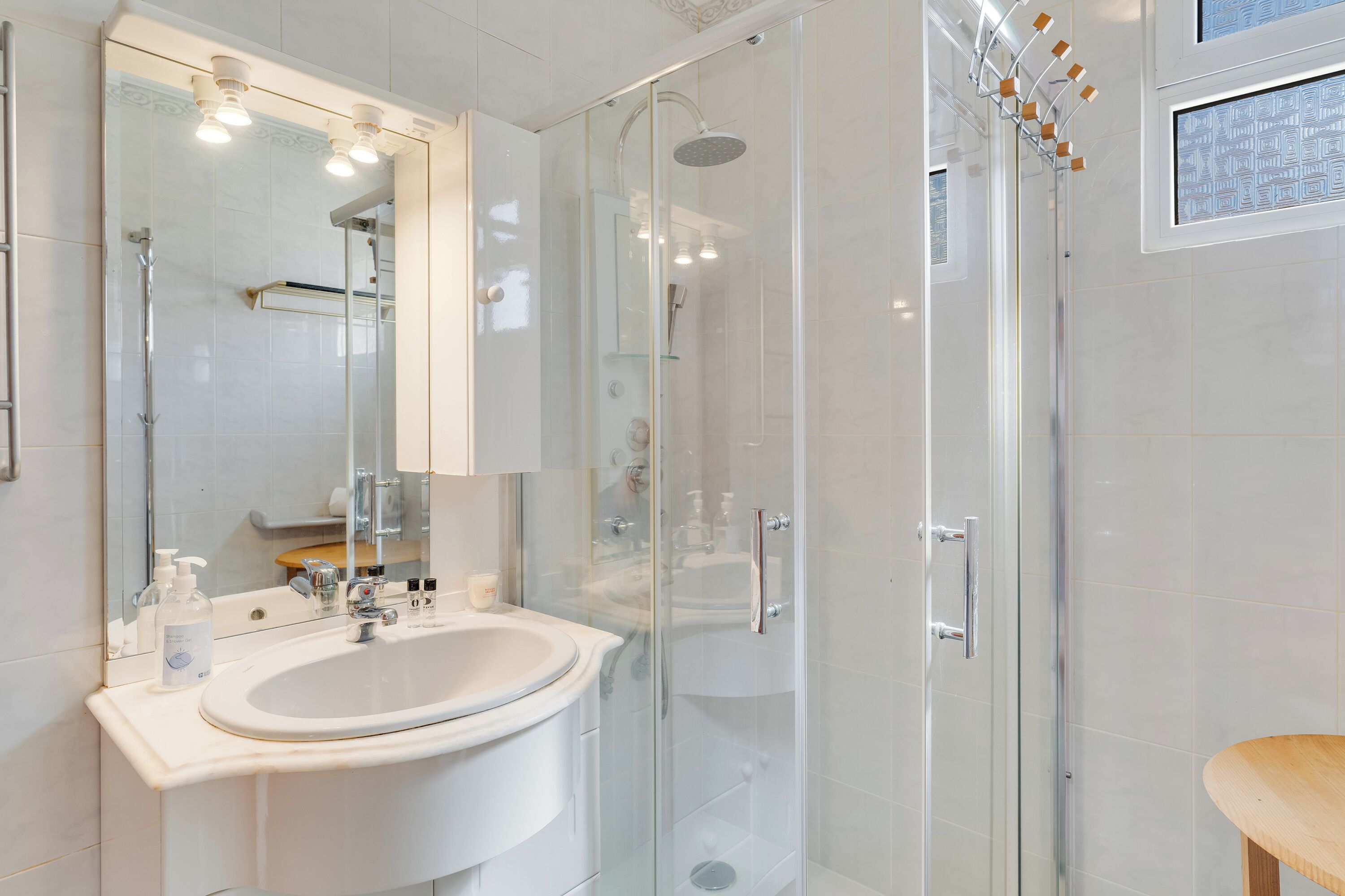 A modern bathroom with a glass-enclosed shower, a white sink, and a mirror.