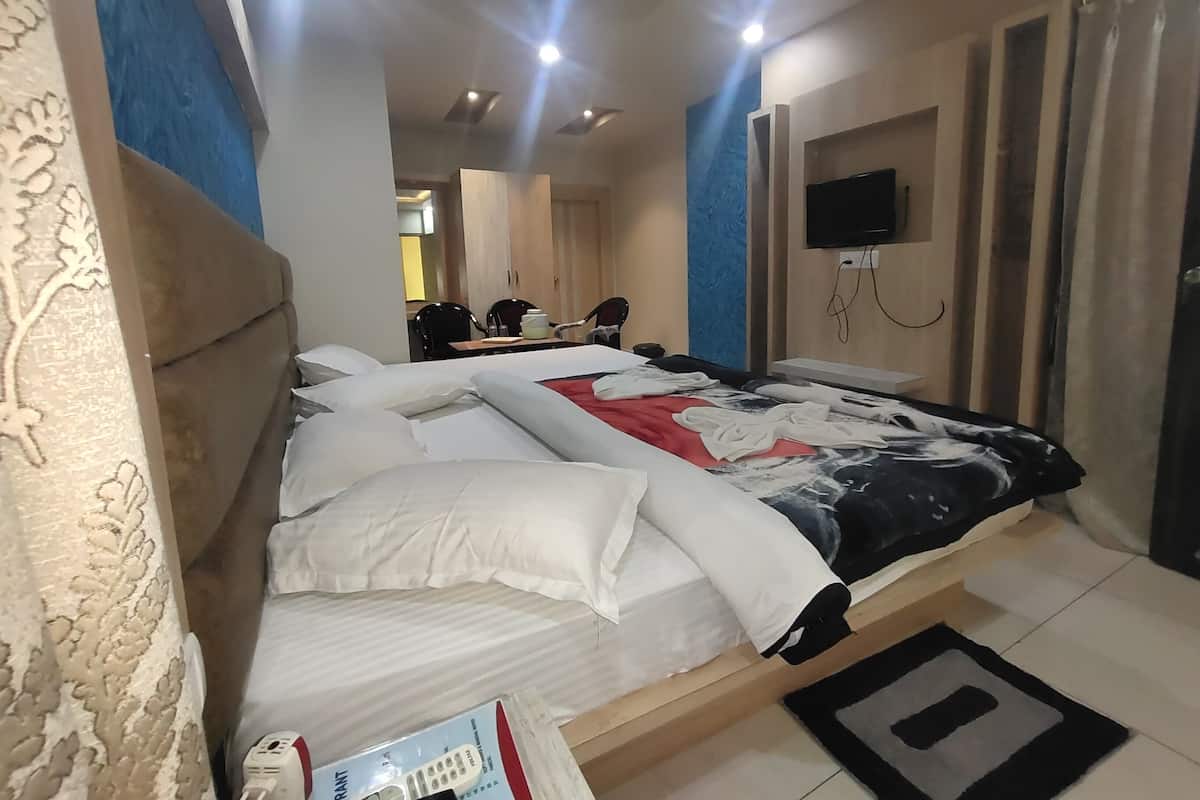 A hotel room with a bed, a TV mounted on the wall, and a desk with chairs.