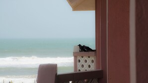 Vista do oceano a partir de uma varanda, com duas aves empoleiradas no corrimão.