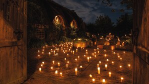 A courtyard with numerous candles, wooden gates, and a building with arched windows. - Le Domaine d'Ablon (Ablon)