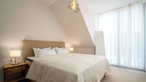 Um quarto com uma cama grande, uma mesa de cabeceira, um abajur e um lustre.