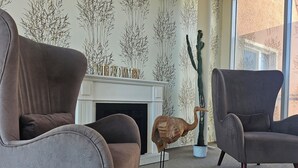 Uma sala de estar com lareira, duas poltronas e uma escultura decorativa.