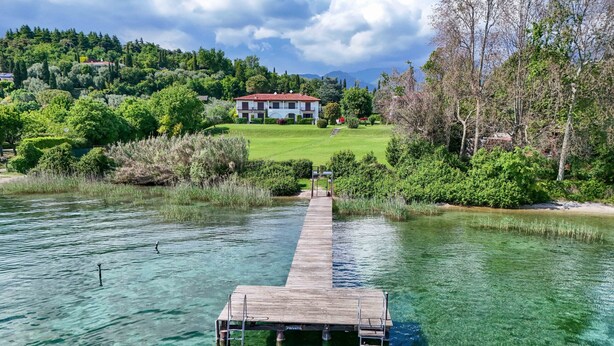 Um lago límpido com um píer de madeira que dá para uma propriedade privada.