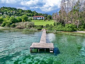 Ein klarer See mit einem Holzsteg, der zu einem Privatgrundstück führt.