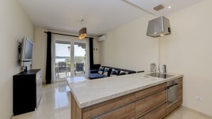 Cozinha moderna com uma ilha grande, forno embutido e um espaço de refeições com sofá.