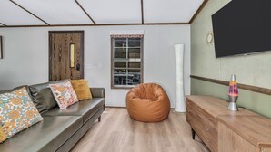 En moderne stue med sofa, saccosek og et fladskærms-tv.