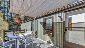 En terrasse med et bord og stole, et lille haveområde og en bygning med dør og vinduer.
