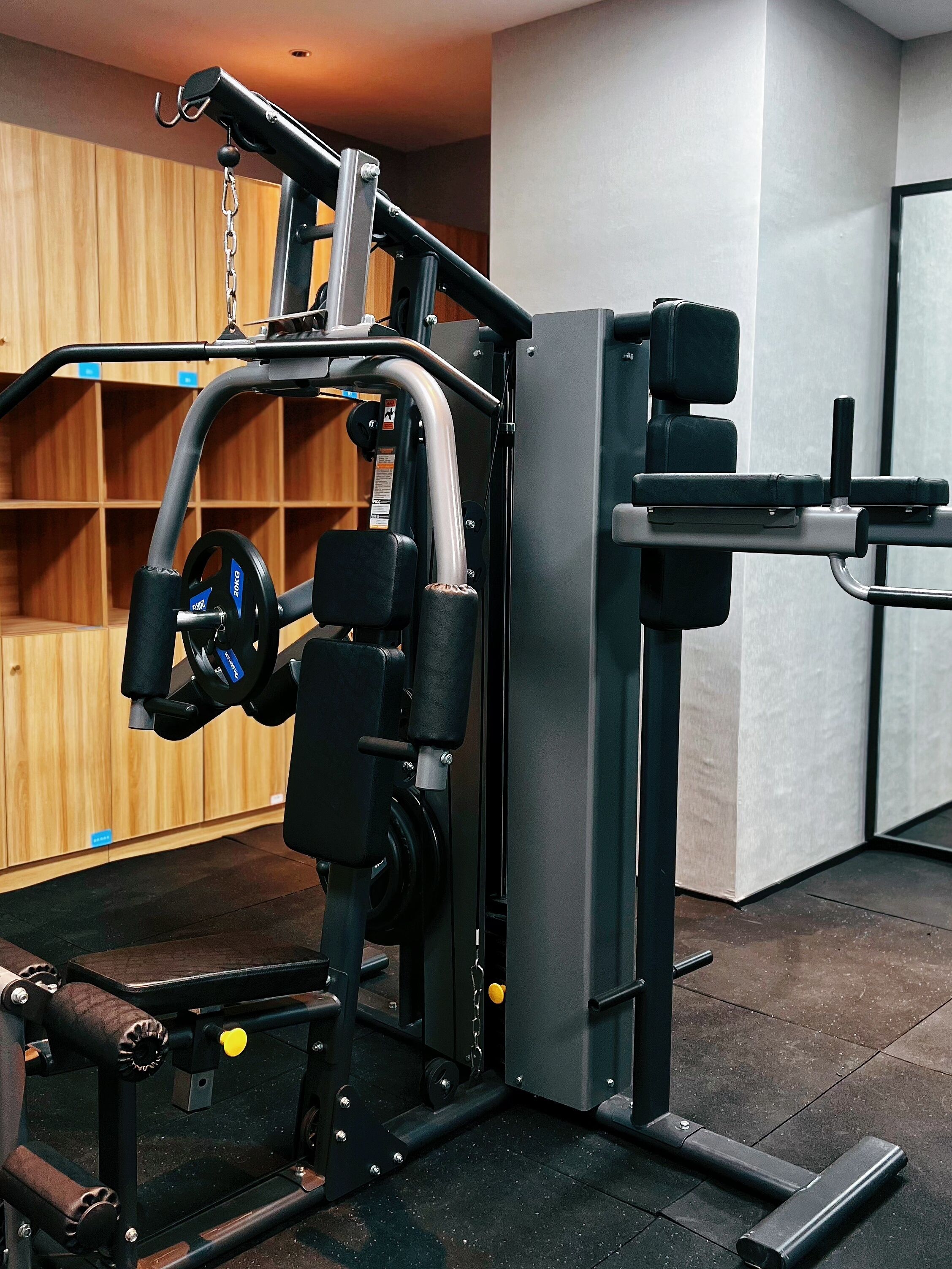 Un gimnasio con equipo de levantamiento de pesas, taquillas de madera y piso de baldosas.
